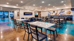 A spacious dining area with multiple tables and chairs, a large TV screen, and a mural on the wall. - Best Western Plus The Inn at Hells Canyon (Clarkston)