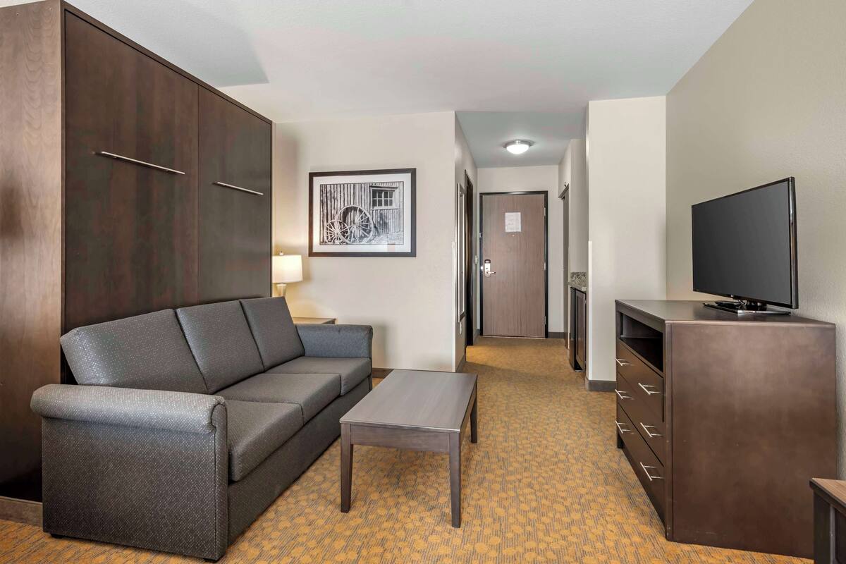 A hotel room with a sofa, a small table, a TV, and a wardrobe.
