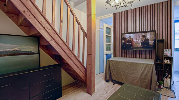 A staircase with wooden railings, a television mounted on the wall, a table with a tablecloth, and a bookshelf with various items. - T2, 48 M2 near the spa (Aix les Bains)