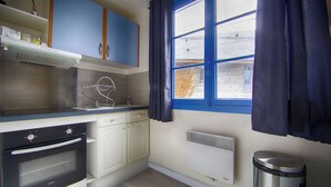 A kitchen with a stove, oven, and a window with curtains. - T2, 48 M2 near the spa (Aix les Bains)