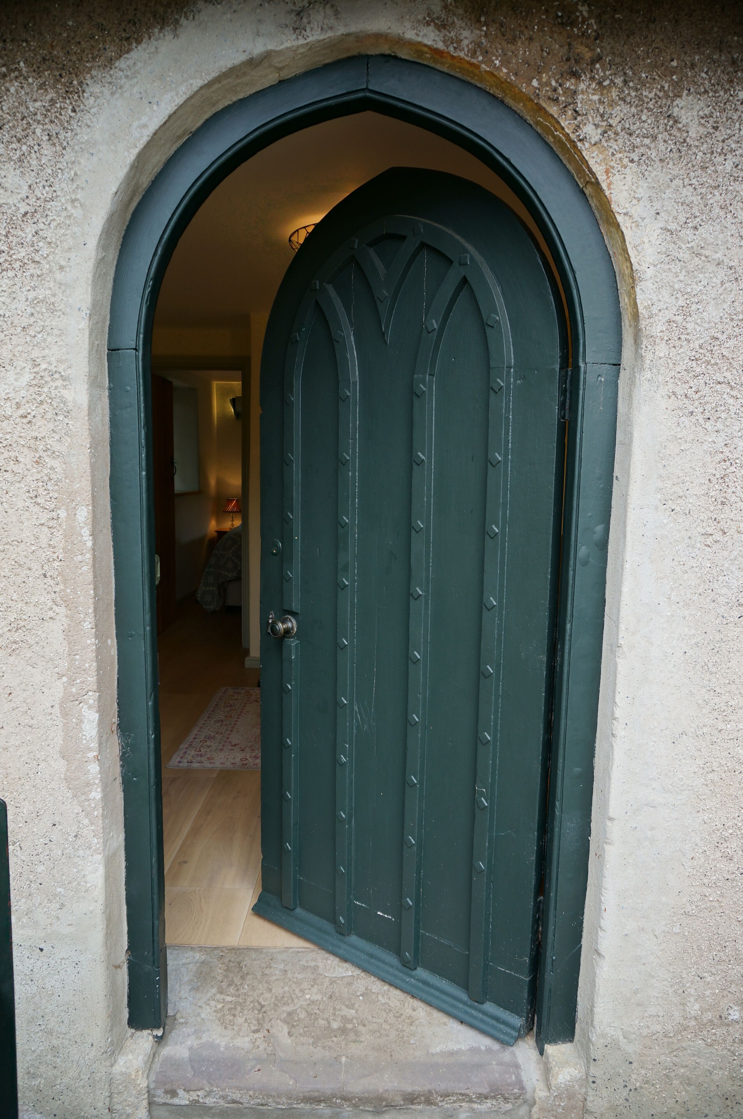 A green door with a metal handle, set in a stone archway.