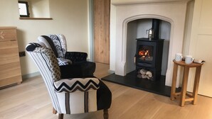 A cozy living room with a fireplace, a striped armchair, and a small wooden table with two mugs.