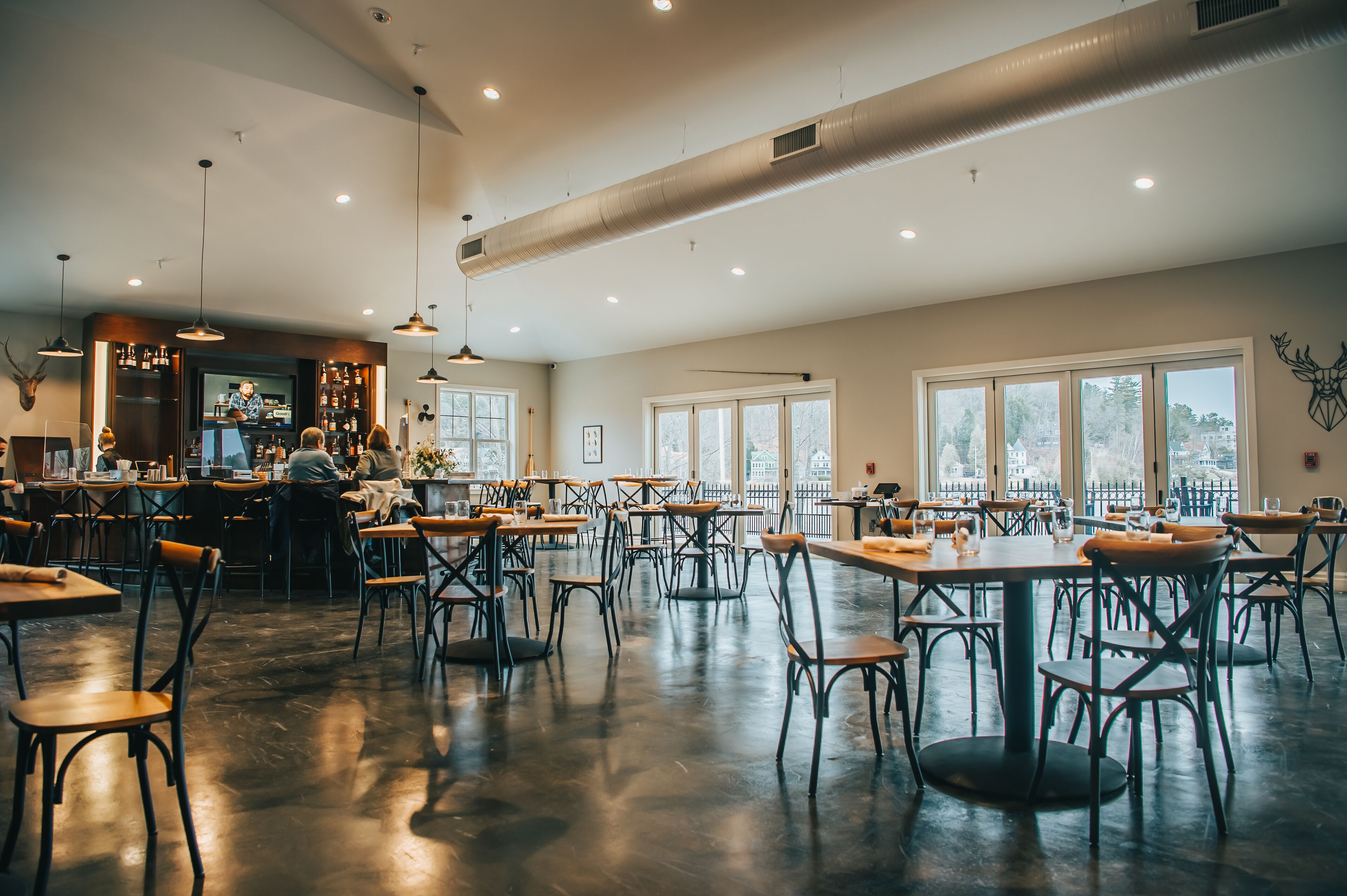 A spacious restaurant with high ceilings, large windows, and a bar area.