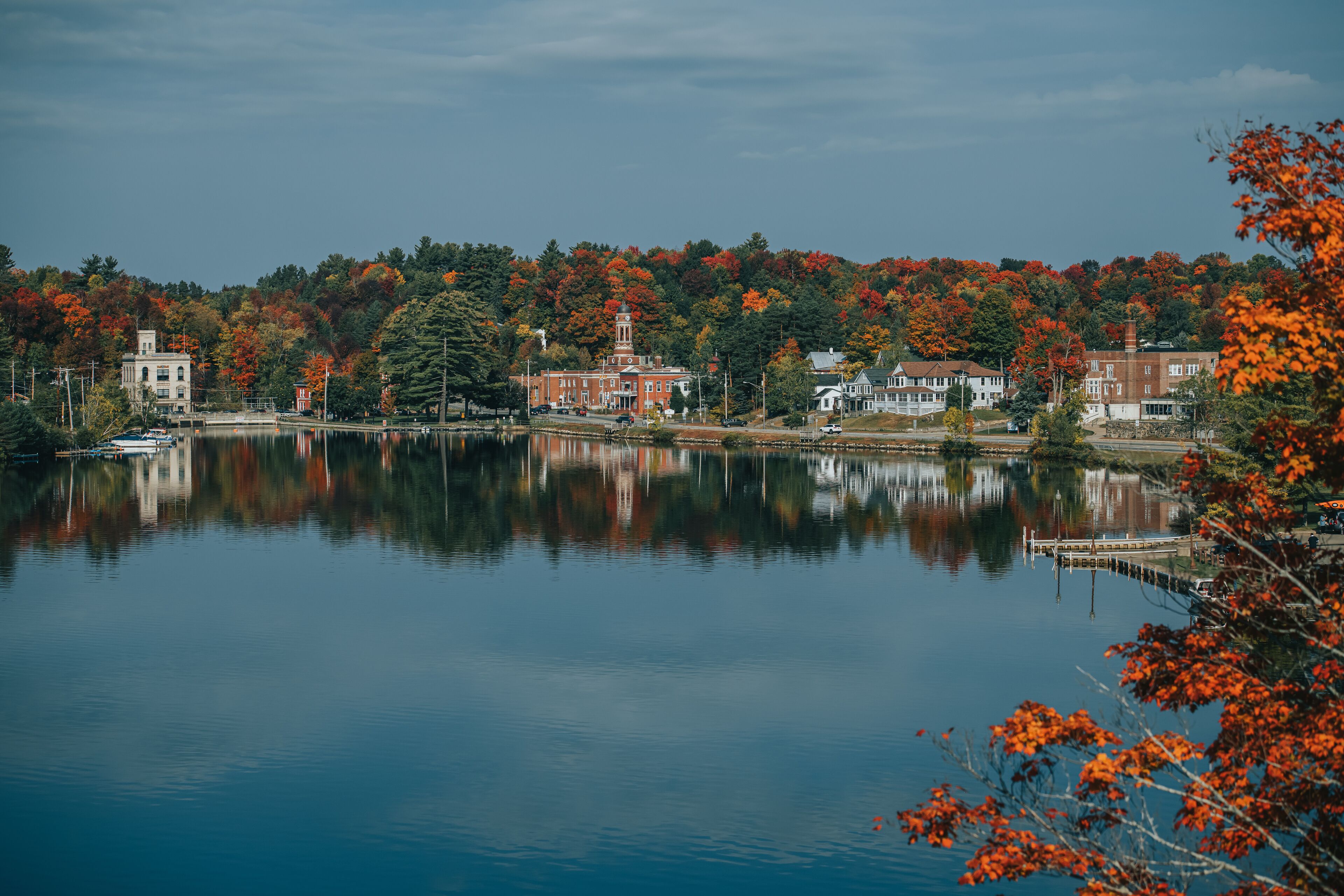 A calm lake with buildings and trees reflecting on the water.