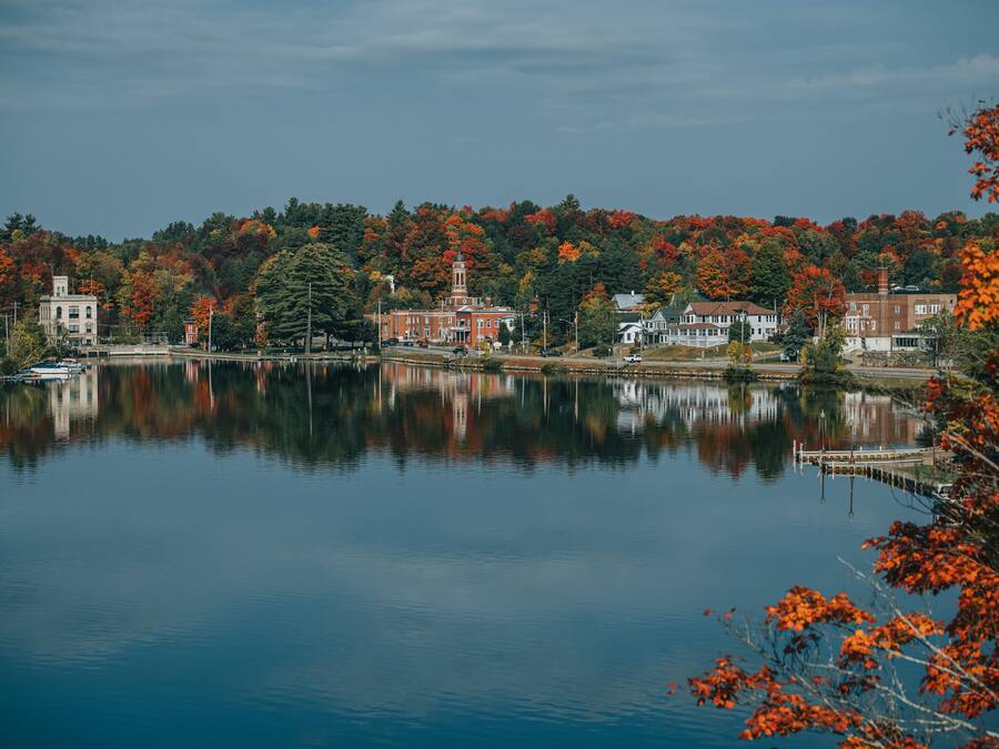 A calm lake with buildings and trees reflecting on the water.