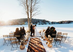 A wedding ceremony outdoors with a snowy landscape in the background.