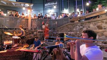 Evento musical al aire libre con un escenario, músicos y un público.