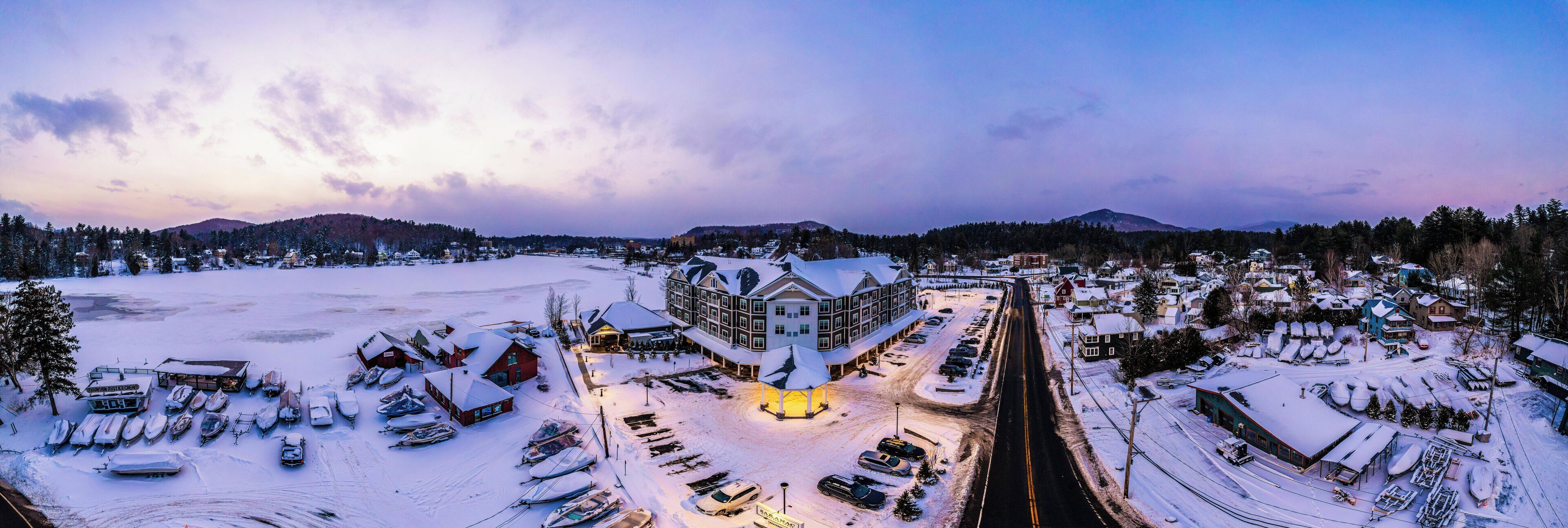 A snow-covered town with a large hotel in the center, surrounded by parked cars and boats.