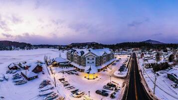 A snow-covered town with a large hotel in the center, surrounded by parked cars and boats.