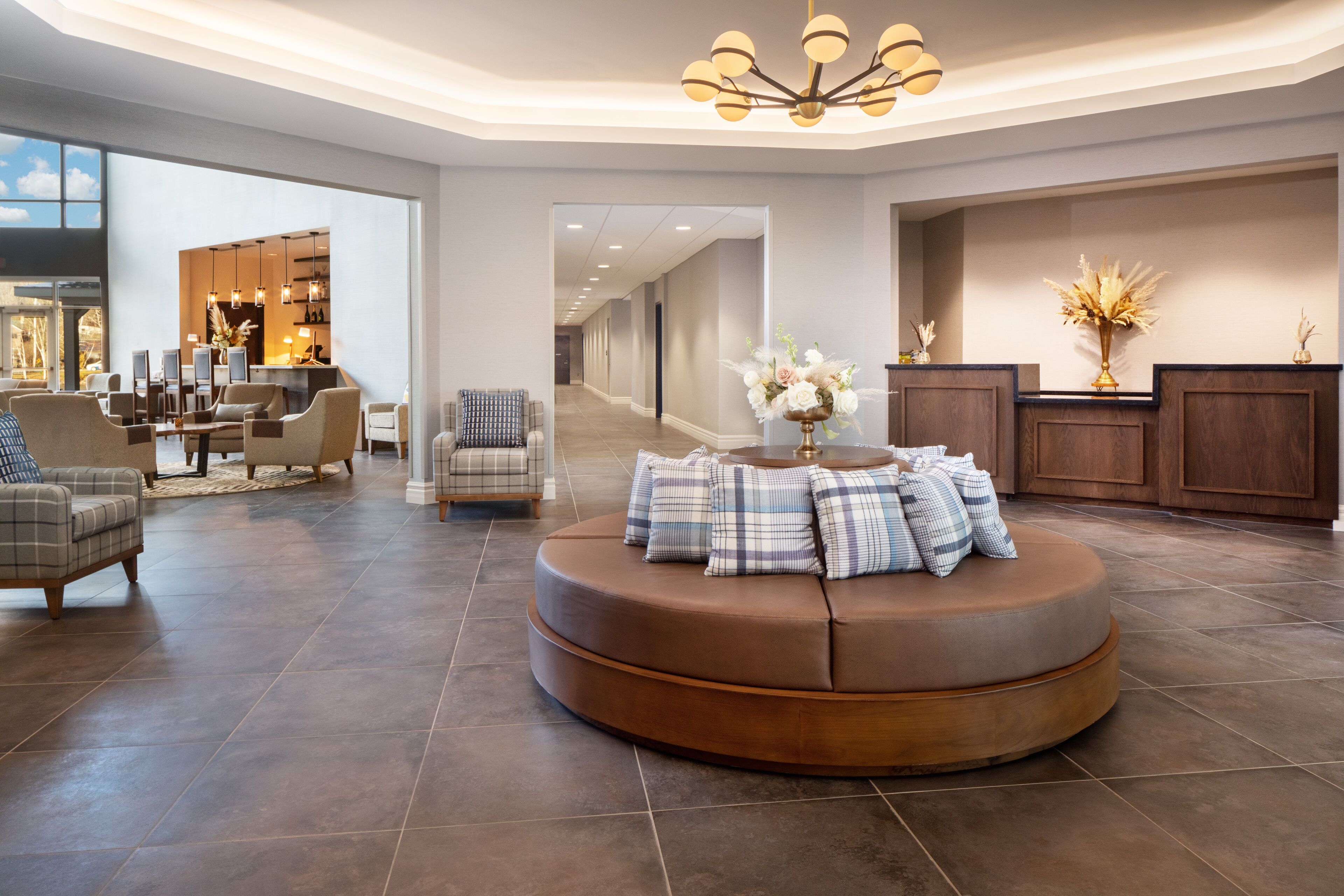 A spacious lobby with a round seating area, a reception desk, and a view into the dining area.