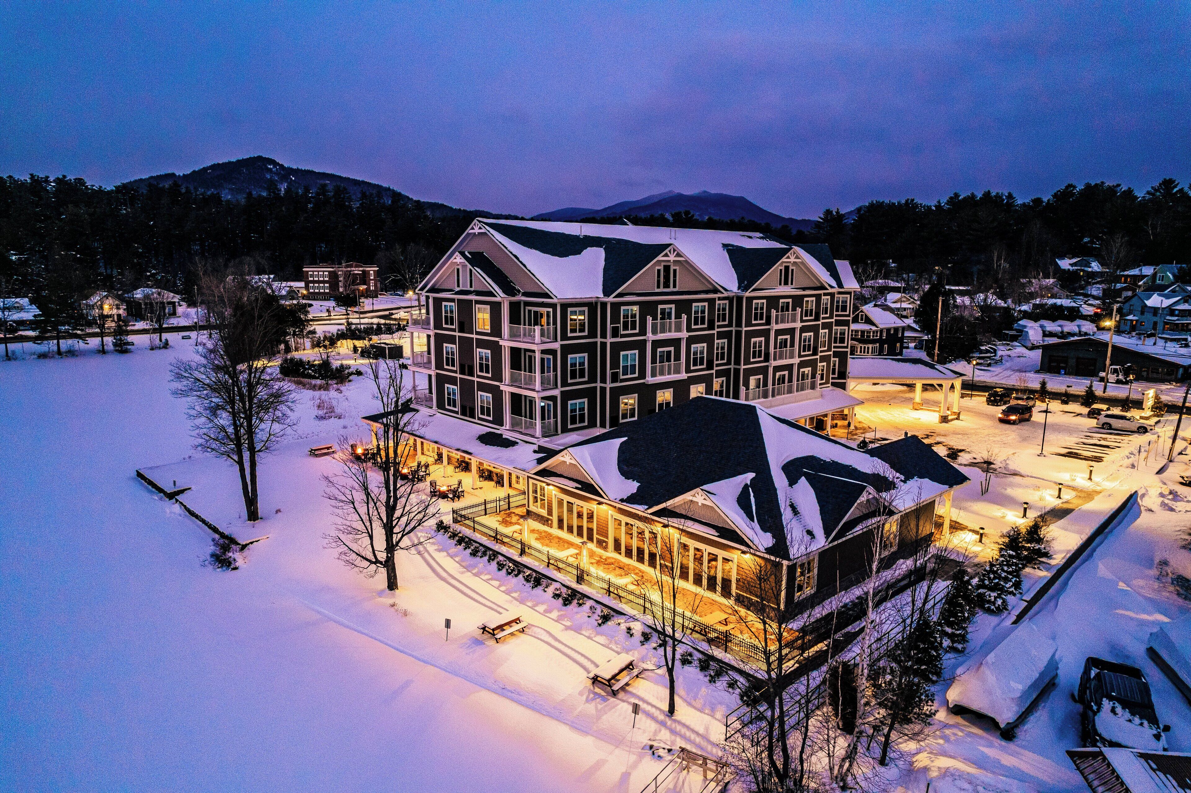 A large, multi-story hotel with a snow-covered roof and a well-lit exterior.