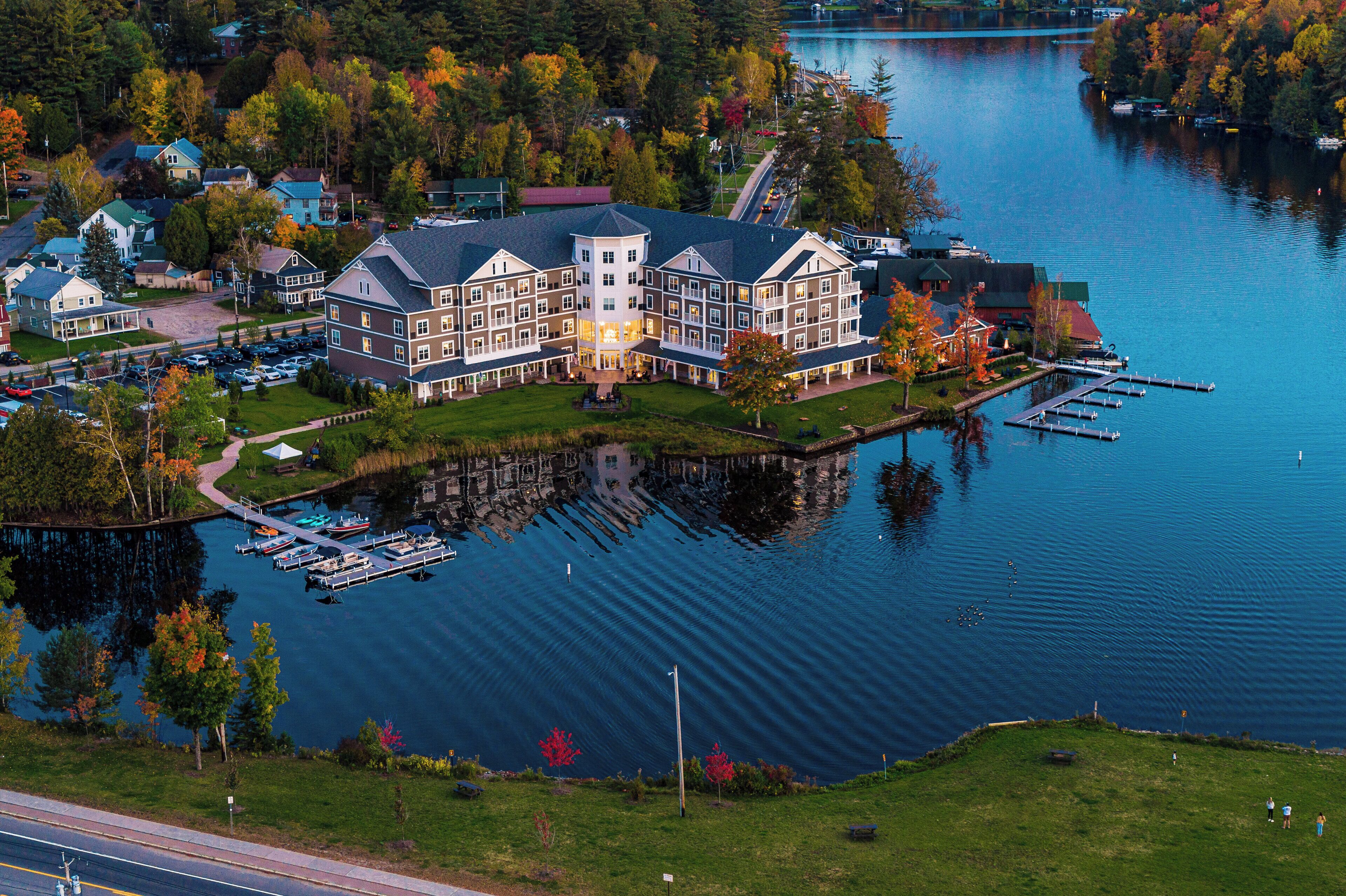 A large, multi-story hotel with a central tower, docked boats, and a lake view.