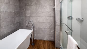 Une salle de bain moderne avec une baignoire sur pieds, une douche en verre et un plancher en bois.