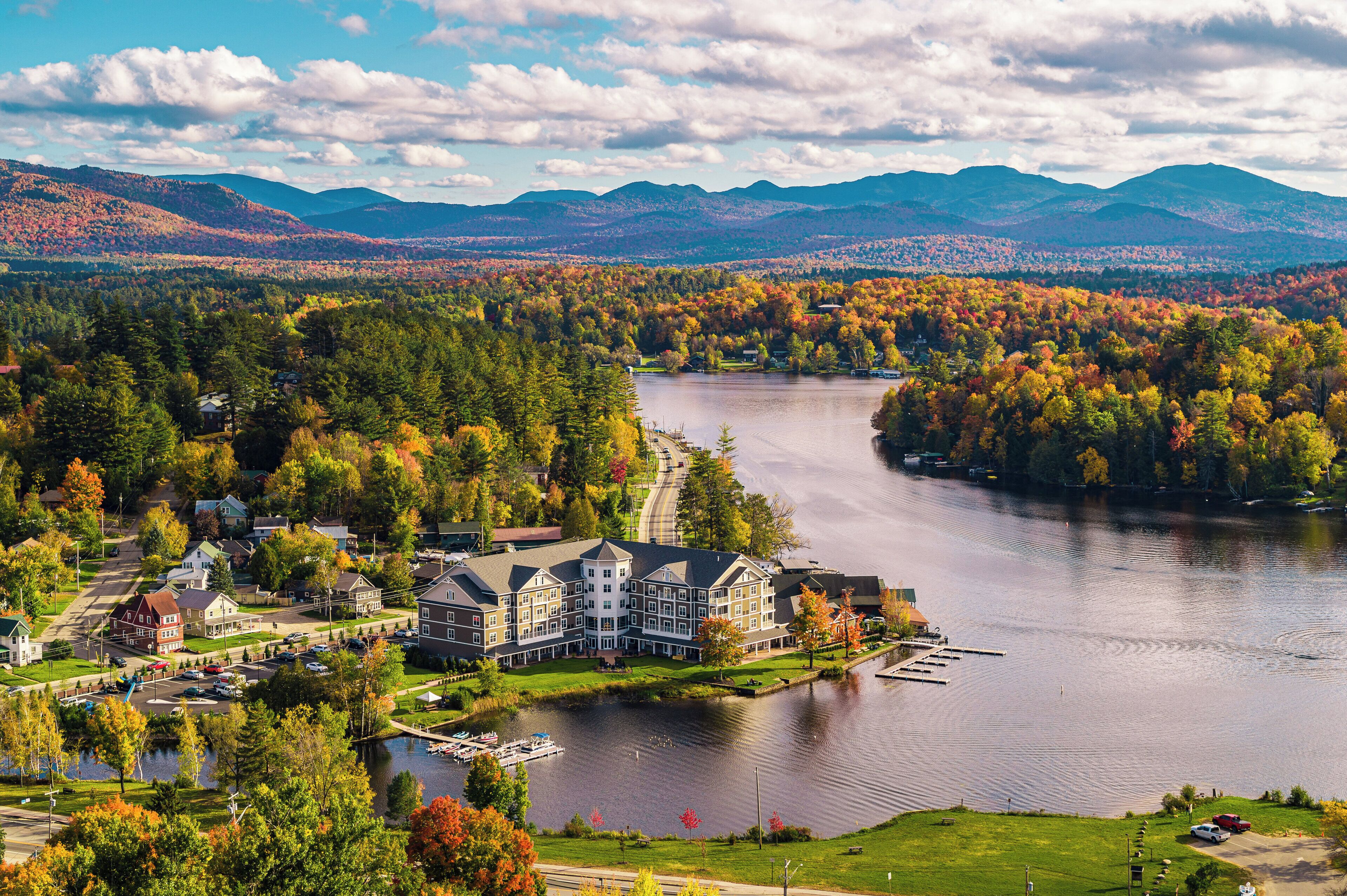 Un gran hotel con varias construcciones, un lago y follaje otoñal alrededor.