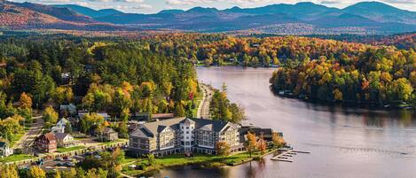 Un gran hotel con varias construcciones, un lago y follaje otoñal alrededor.