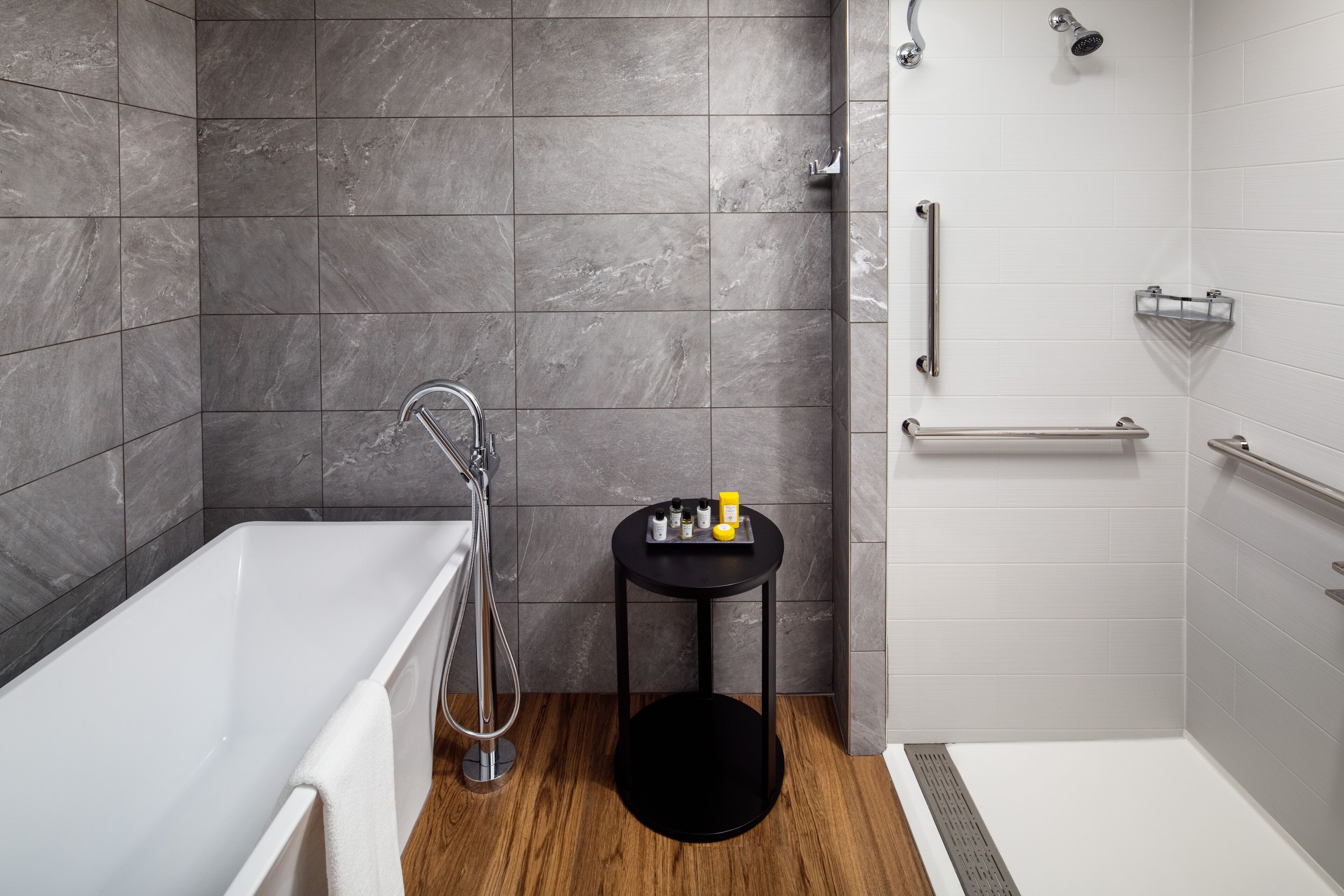 A modern bathroom with a bathtub, a shower, and a small table with toiletries.