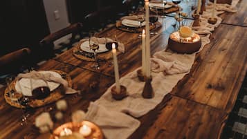 A long wooden table set for a meal with candles, plates, and glasses.