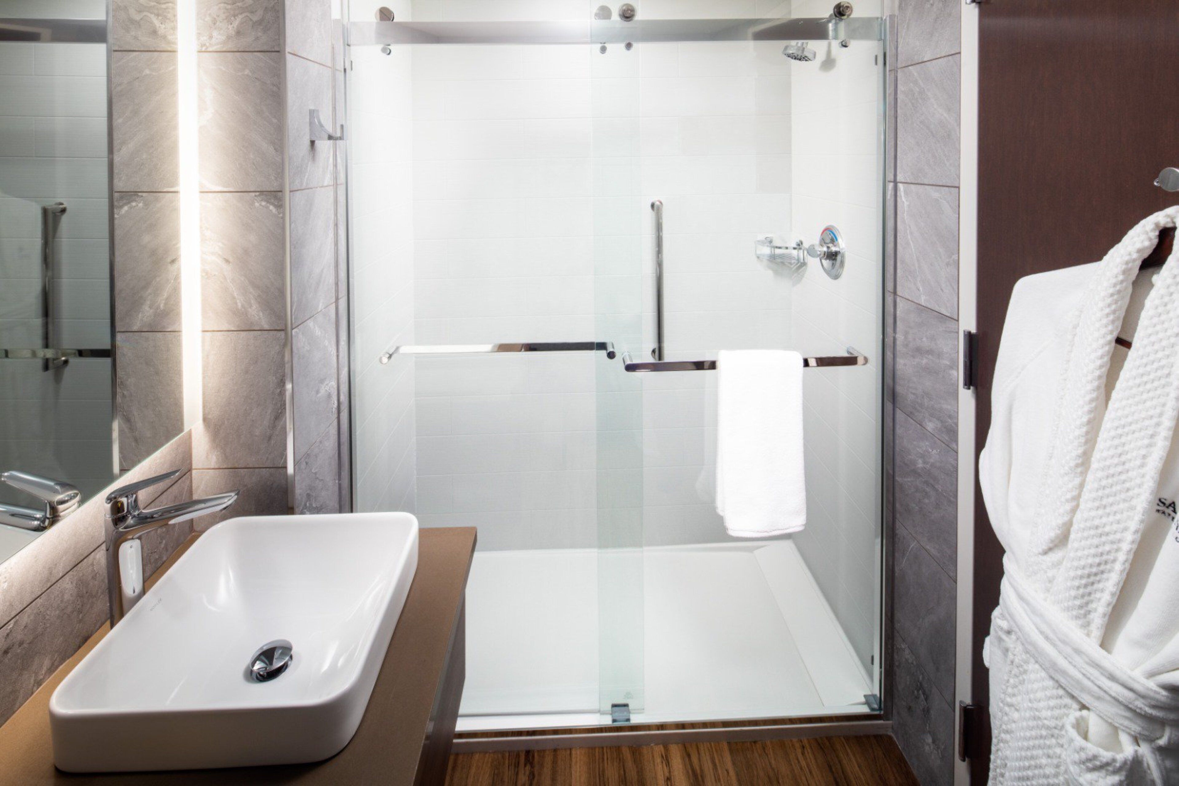 Une salle de bain moderne avec une douche à parois de verre, un lavabo blanc et un meuble-lavabo en bois.