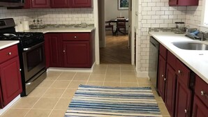 Una cocina con armarios rojos, un lavamanos de acero inoxidable y un salpicadero de azulejos.