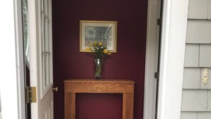 Una consola de madera con un jarrón de flores amarillas frente a una pared color burdeos.
