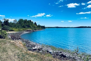 Paesaggio naturale con un lago blu intenso, riva rocciosa e fitta foresta.