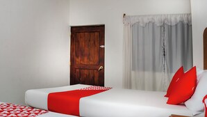 A bedroom with a wooden door, a window with sheer curtains, and a bed with white bedding and red accents. - OYO Hotel Miramar, Loreto (Loreto)