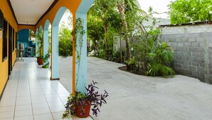A covered corridor with tiled flooring, blue and yellow walls, and potted plants. - OYO Hotel Miramar, Loreto (Loreto)