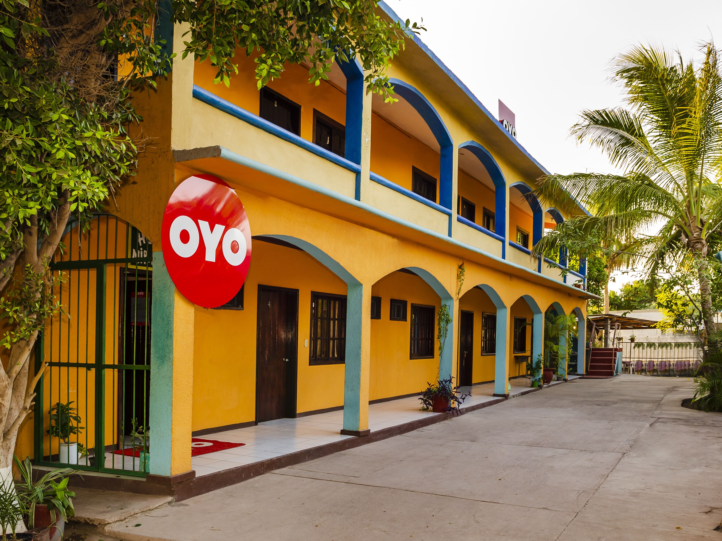 Un edificio de dos pisos con fachada amarilla y detalles azules, que presenta un letrero destacado de 'OYO'.