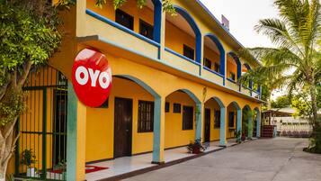 Un edificio de dos pisos con fachada amarilla y detalles azules, que presenta un letrero destacado de 'OYO'.