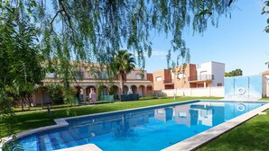 Una piscina rectangular con una superficie de agua azul cristalina, rodeada de césped y árboles bien cuidados.