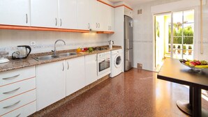 Een moderne keuken met witte kasten, een granieten aanrecht, een roestvrijstalen koelkast, een inbouwoven en een wasmachine.