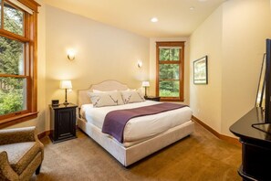 A bedroom with a large bed, two bedside tables with lamps, a chair, and a desk.