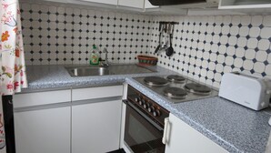 A compact kitchen with white cabinets, a gas stove, a built-in oven, and a toaster.