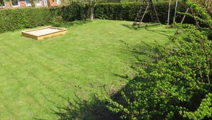 A well-maintained backyard with a wooden play structure, a raised garden bed, and a lawn.