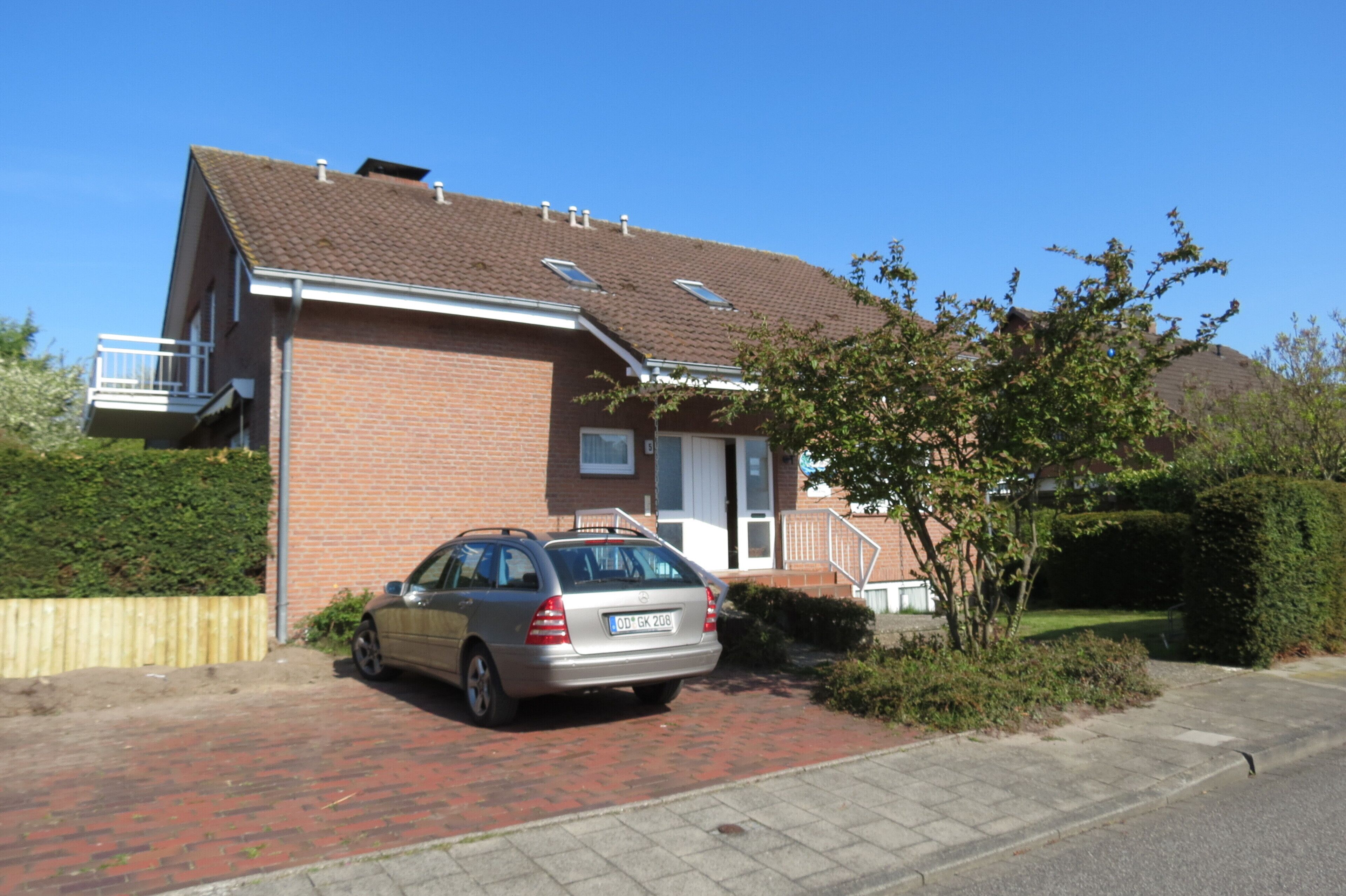 A two-story house with a car parked in the driveway.