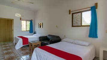 Habitación de hotel con dos camas, un ventilador de techo, una ventana con cortinas y una mesita pequeña.
