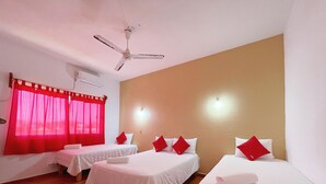A hotel room with three single beds, each with white bedding and red pillows, a ceiling fan, and red curtains. - Hotel y Bungalows Bugambilias (San Patricio Melaque)