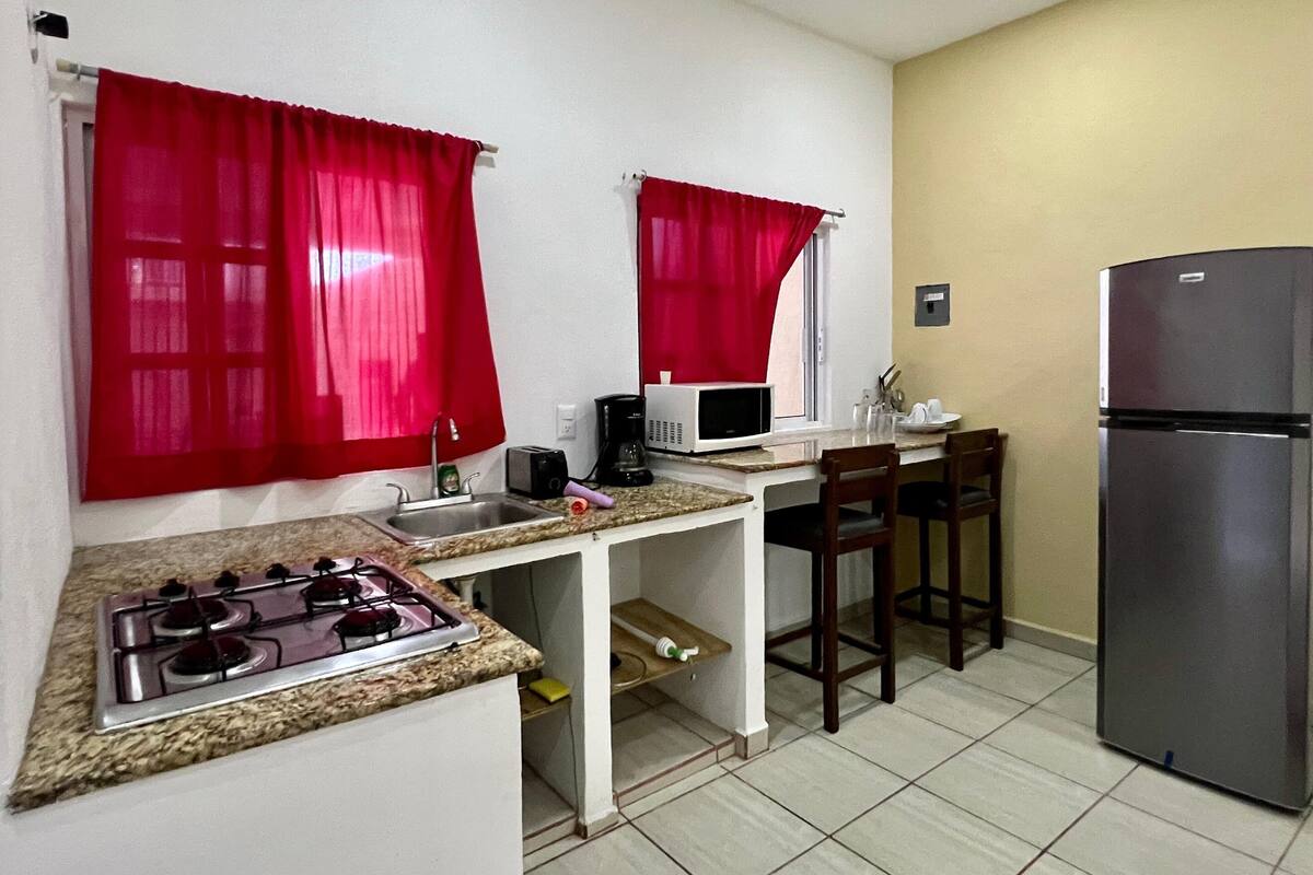 A compact kitchen with a gas stove, microwave, sink, and a refrigerator.