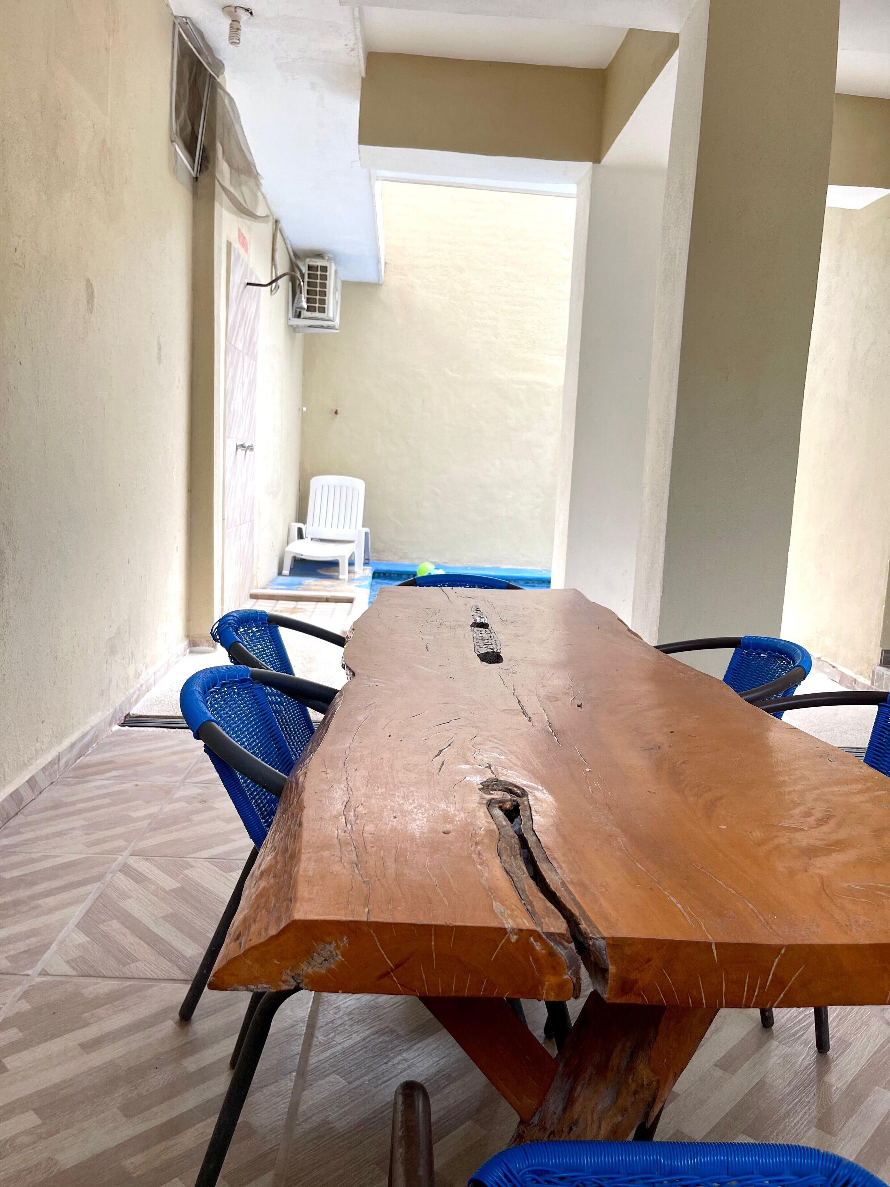 Un salón de conferencias con una gran mesa de madera, sillas azules y una silla blanca.