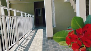 A corridor with tiled flooring, a white railing, and a staircase leading to an upper level. - Hotel y Bungalows Bugambilias (San Patricio Melaque)