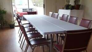 Une salle de conférence avec une longue table et des chaises, une nappe blanche et des plantes en pot disposées sur la table.