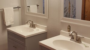 Une salle de bain avec deux lavabos, un miroir et un rideau de douche.