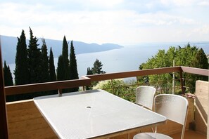 Enjoy serene lake views and mountain vistas from this balcony with a table and chairs.