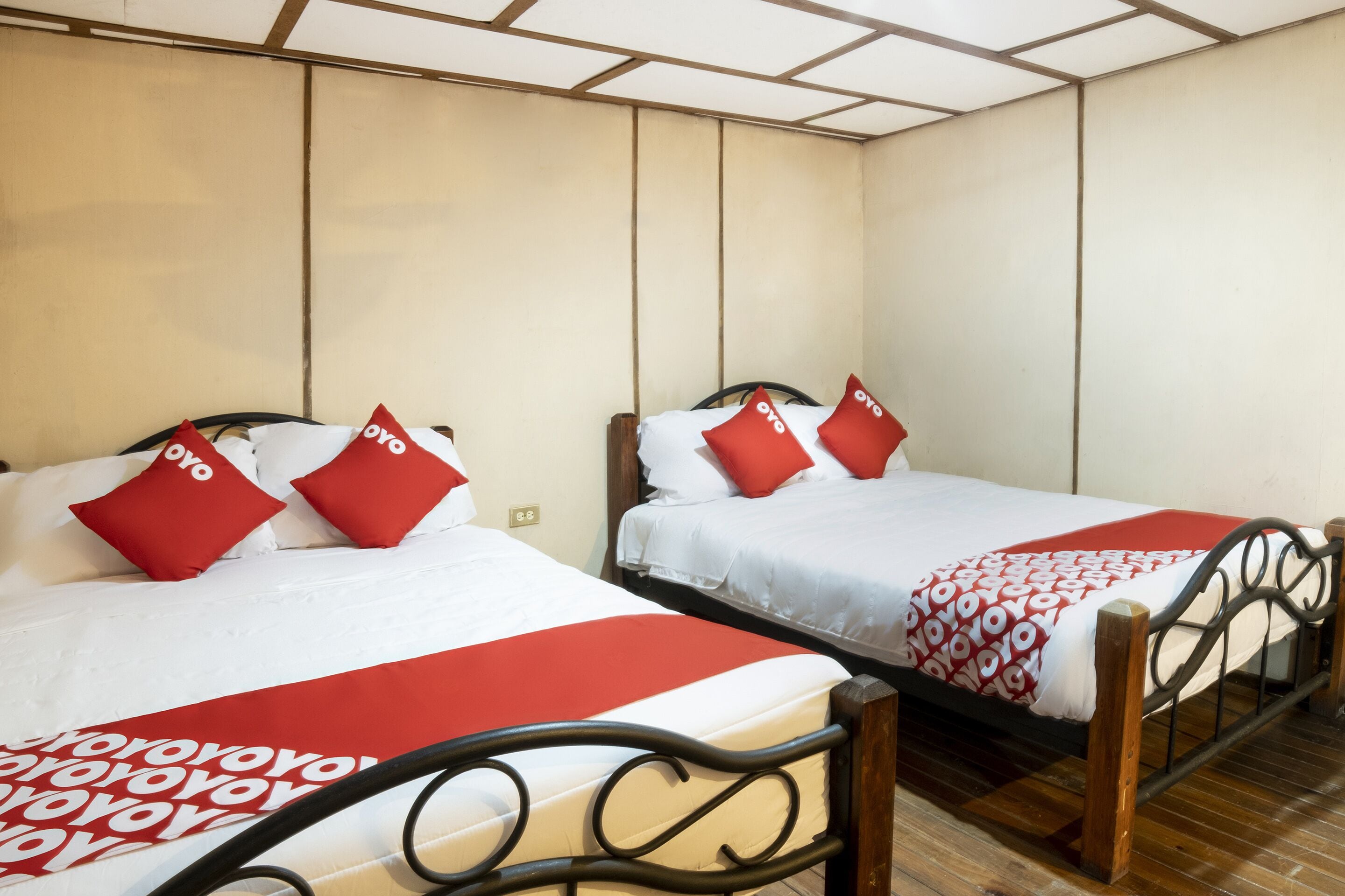 Two single beds with red and white bedding, wooden headboards, and a tiled ceiling.