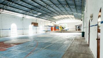 Un gimnasio interior con techo alto, una cancha de baloncesto y una zona de asientos.