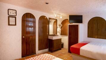 A room with two beds, wooden doors, a television, and a tiled floor.