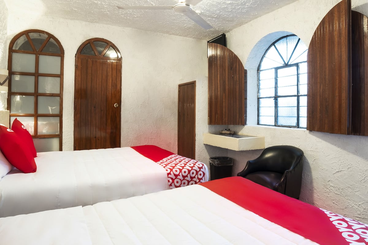 Habitación de hotel con dos camas, un escritorio pequeño, una silla y una ventana con vistas.