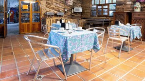 A rustic wooden interior with tiled flooring, metal chairs, and tables set with tableware.