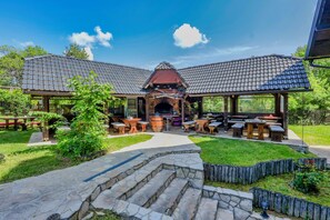 A covered outdoor dining area with stone steps leading to a central seating area, surrounded by greenery. - Luxury room in Plitvice lakes (Plitvice lakes)