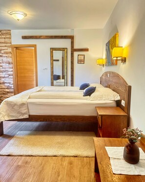 Un dormitorio con cama de madera, mesita de noche, espejo, lámpara de pared y pared de piedra.